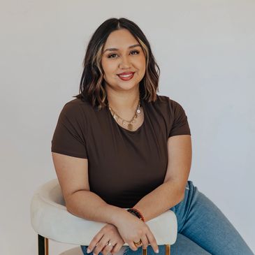 Smiling woman with shoulder-length hair sitting on a white chair.