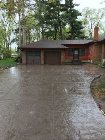 Stamped concrete driveway looks like Stone in this wooded setting.