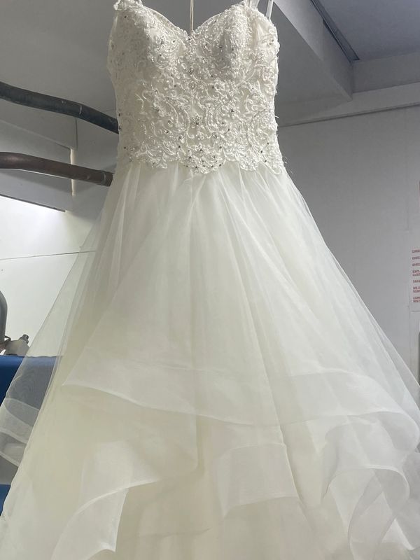 Elegant white wedding dress with intricate lace bodice and flowing tulle skirt.