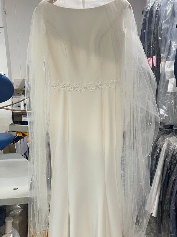 Elegant white wedding dress with sheer long sleeves and delicate waist embellishment.