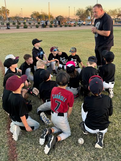 Coach talks to young baseball team on field.