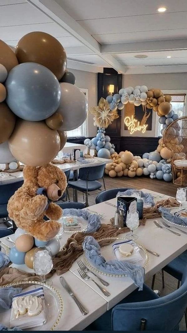 Elegant baby shower setup with teddy bear and blue, beige balloons.