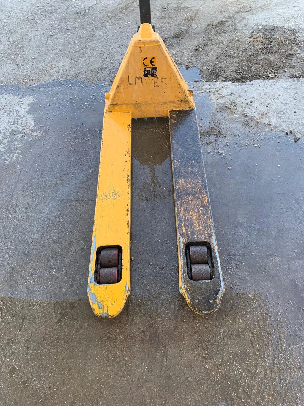 Yellow and black pallet jack on a concrete floor.