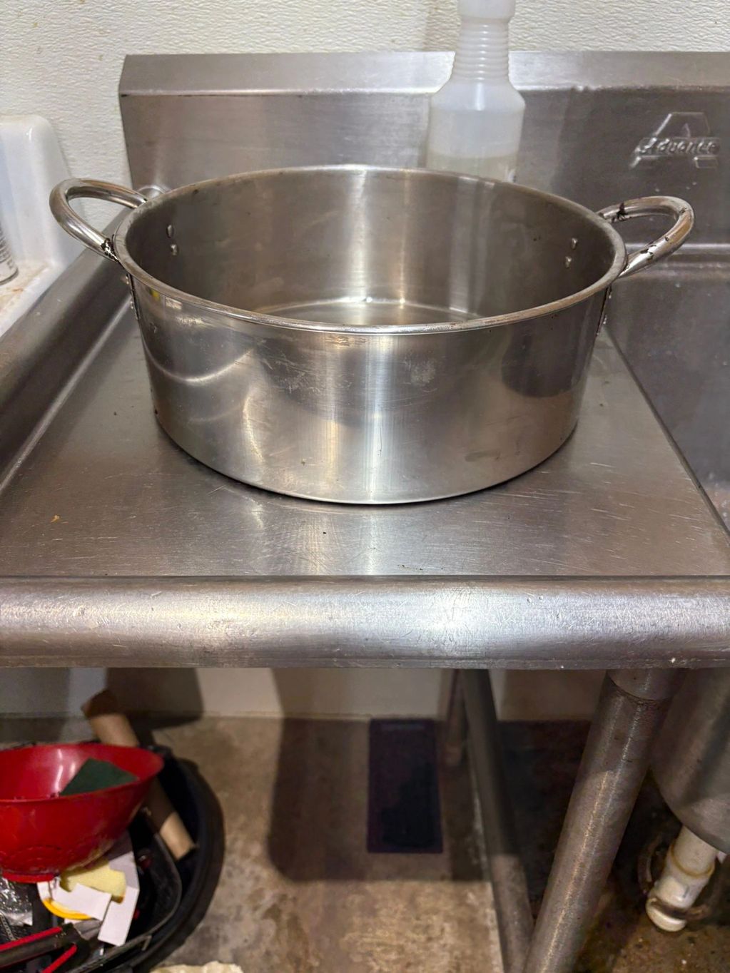 A stainless steel pot on a stainless steel sink in a kitchen.