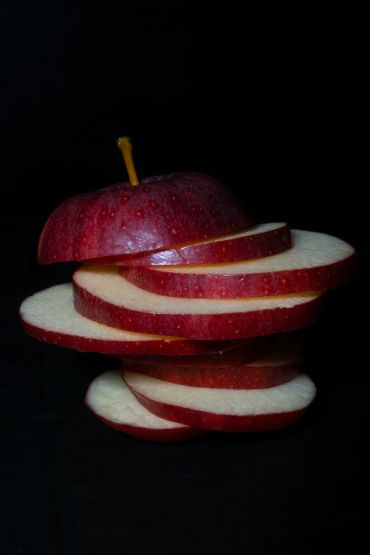Sliced red apple stacked against a black background.
