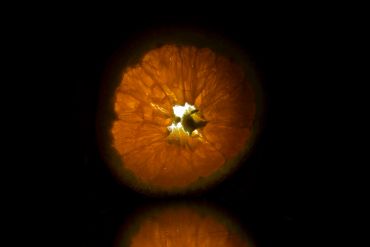 Illuminated cross-section of an orange against a black background.