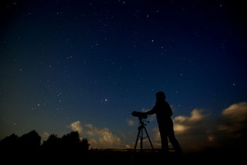 Person setting up a telescope on a starry evening