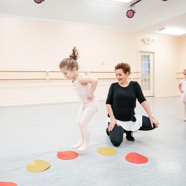 Young dancer jumping on dots in ballet class