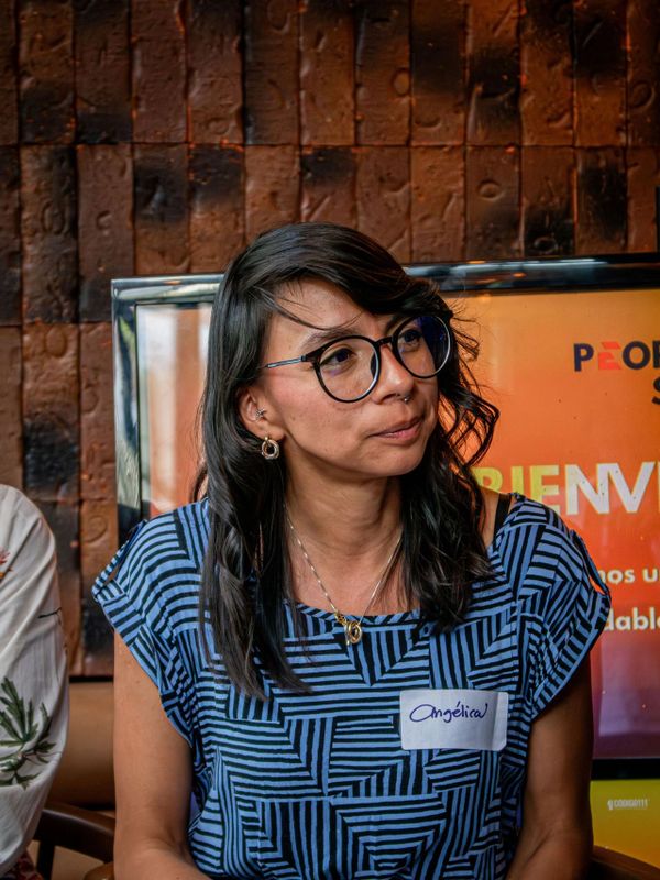 Woman wearing glasses and a name tag with a thoughtful expression.