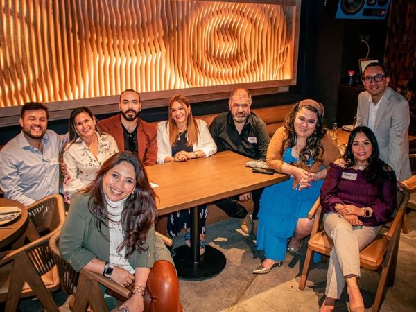 Group of nine people smiling and posing at a restaurant table.