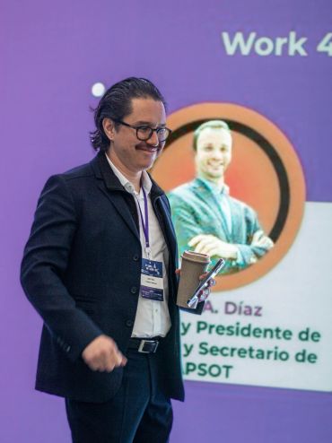 Hombre con gafas sonriente en conferencia.