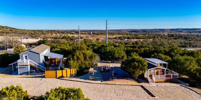 Two houses with patios in a Texas Hill Country, open landscape.