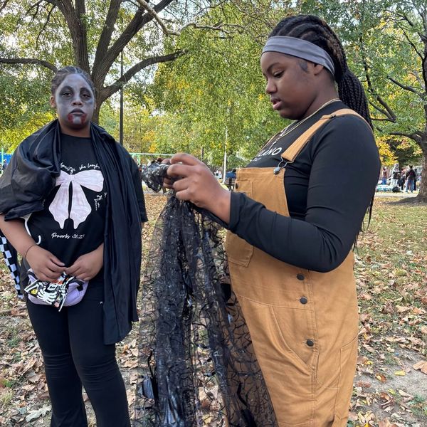 Two girls preparing Halloween costumes outdoors.
