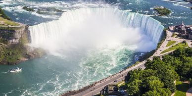 Aerial view of Niagara Falls with mist and surrounding greenery.