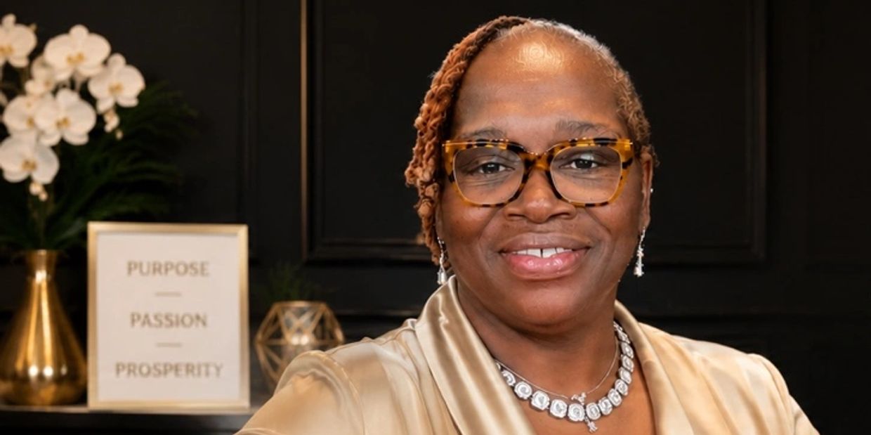 Woman smiling with tortoiseshell glasses and jewelry.