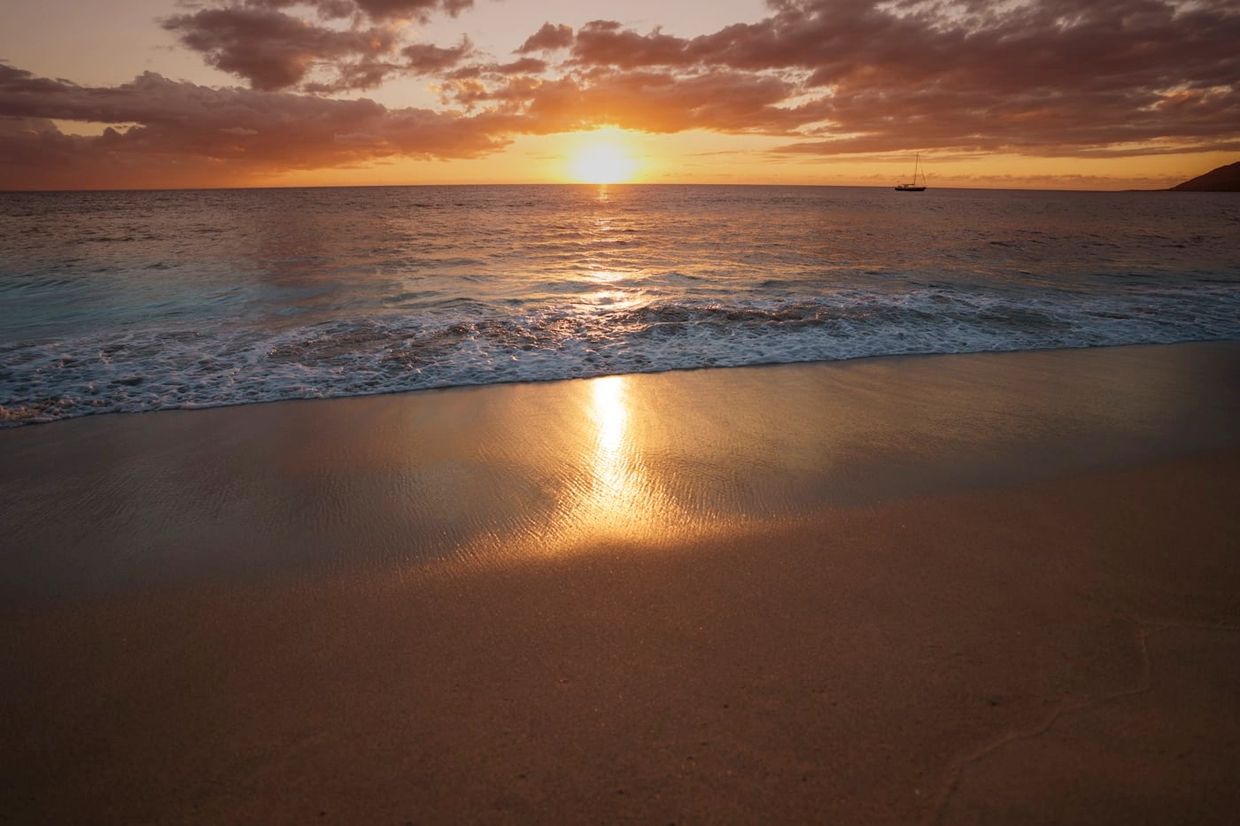 Golden sunset over a serene beach with gentle waves.