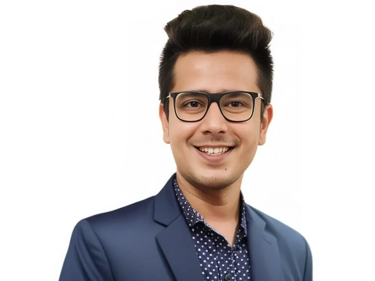 Smiling young man in glasses and a navy blazer.