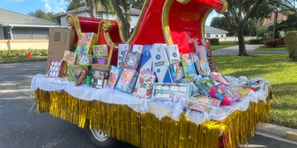 A festive red sleigh filled with toys and gifts on a suburban street.