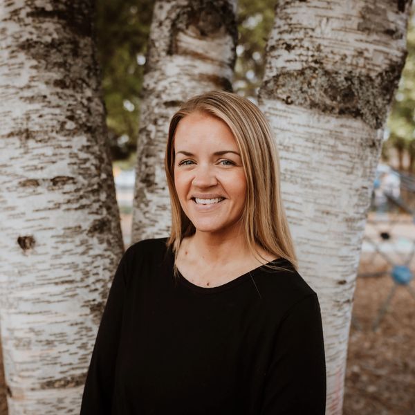 Smiling woman standing by birch trees.