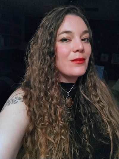 Woman with long curly hair and red lipstick.