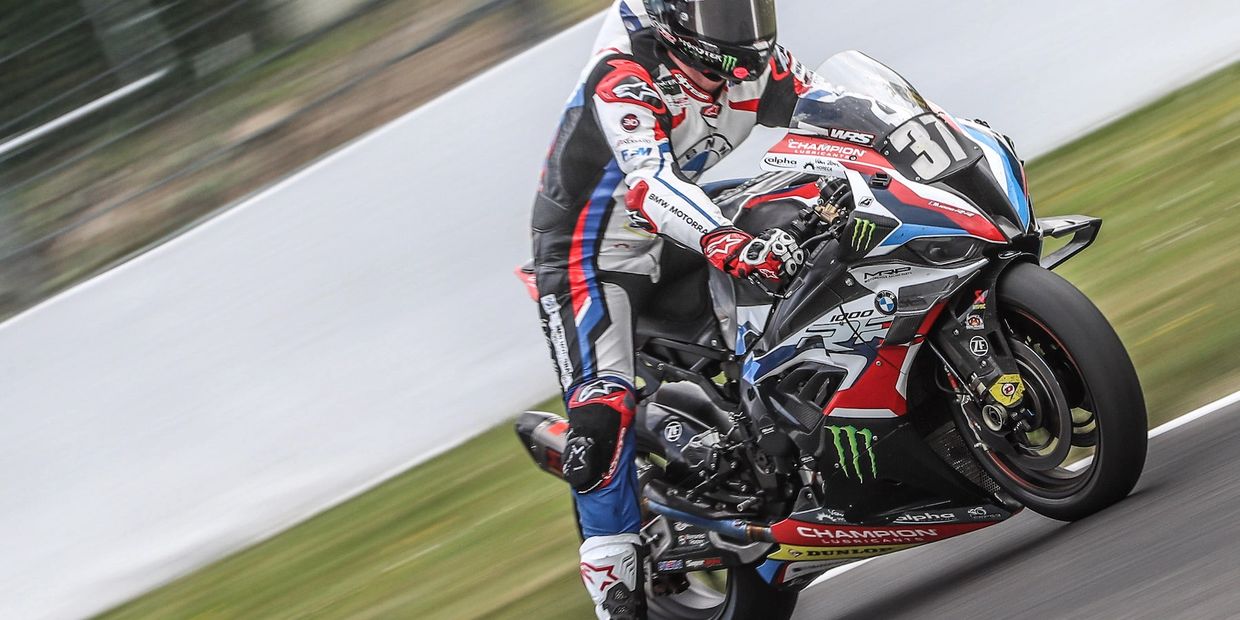A motorcycle racing around a track. The motorbike and rider are in focus, background blurred