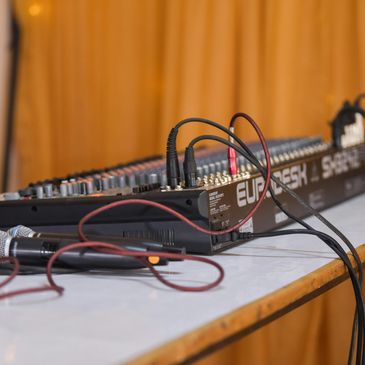 Audio mixer and microphone on a table with cables.