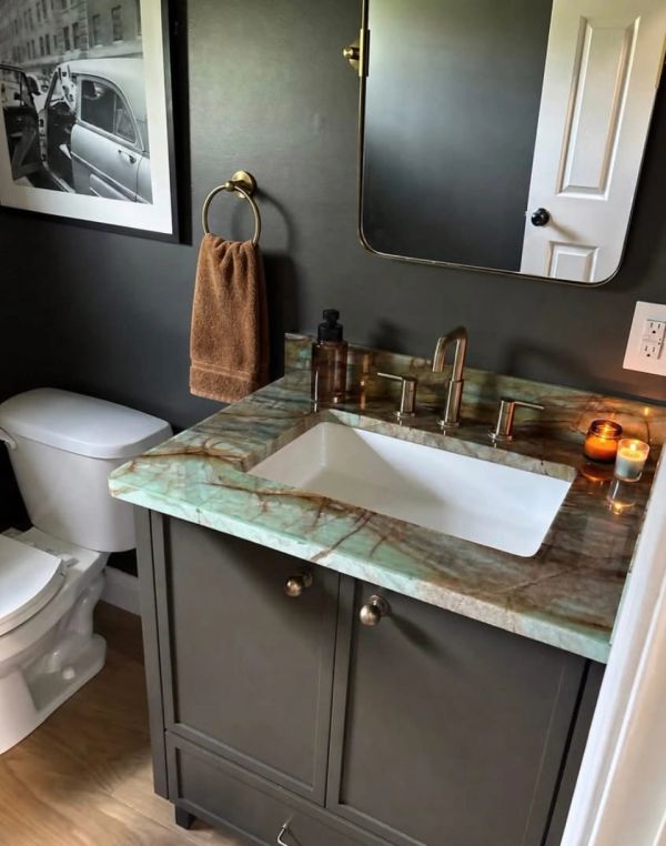 Modern bathroom with marble countertop and dark walls.