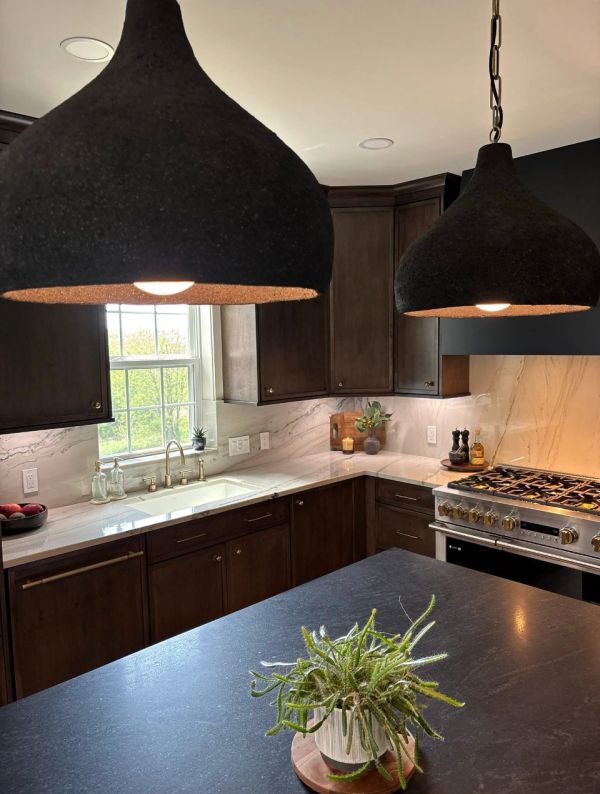 Modern kitchen with dark cabinets and pendant lights.
