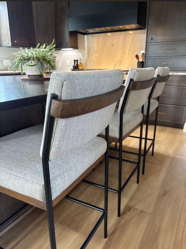 Three cushioned bar stools in a modern kitchen.