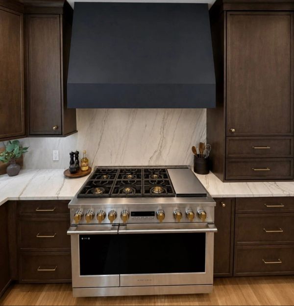 Modern kitchen stove with marble backsplash and dark wood cabinets.