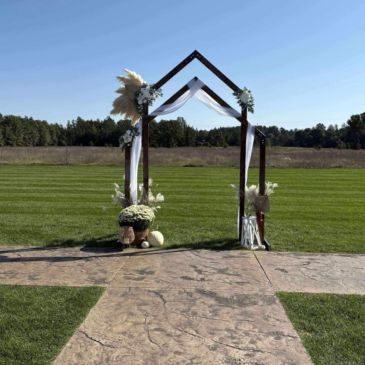 Decorated wedding arch outdoors on a sunny day.