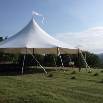 A white canopy tent set up on a grassy hill under a blue sky.