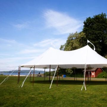 Large white event tent set up on green grass under a clear blue sky.