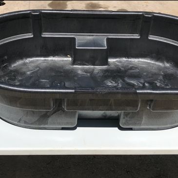 Large black plastic pond liner on a white table outdoors.