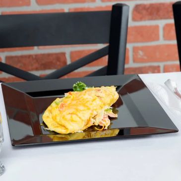 Cheese-covered omelette served on a black square plate.