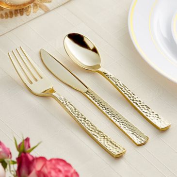 Elegant gold hammered flatware set on a white tablecloth.