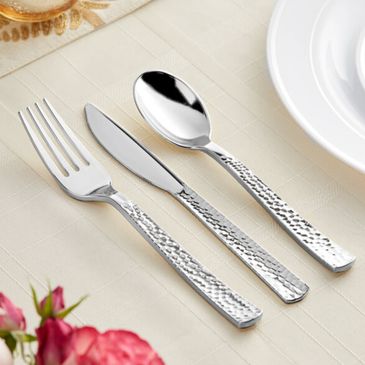 Hammered texture silverware set with fork, knife, and spoon on a white tablecloth.