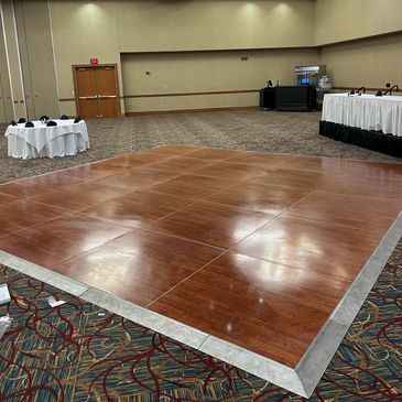 Empty event space with wooden dance floor and round table.