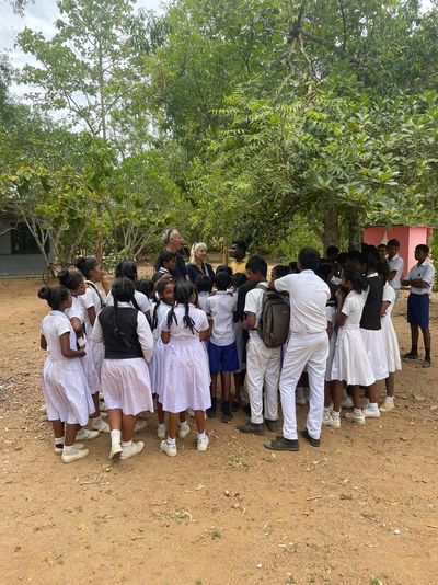 A group of students gathered outdoors under a tree.