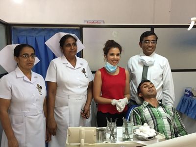 Group photo in a dental clinic with staff and a patient.