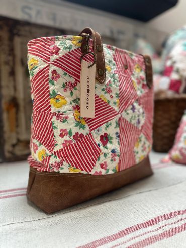 Colorful quilted handbag with leather bottom and tag.