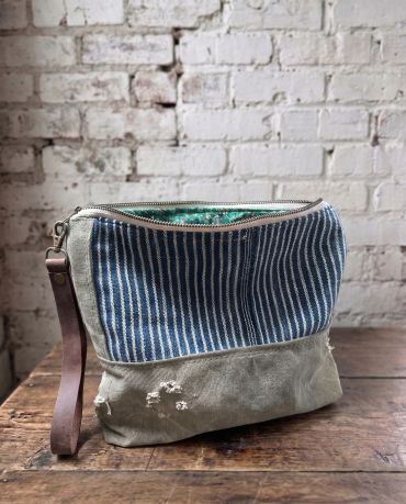 Canvas and striped fabric pouch with leather strap.