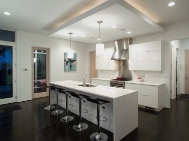 Modern kitchen with white island and bar stools.