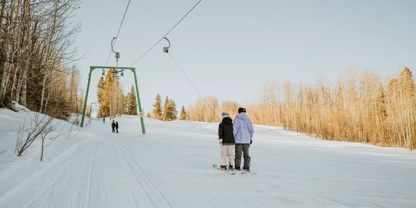 Two skiers using a ski lift on a snowy slope.