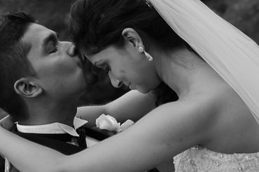 black and white photo of a groom kissing his bride's forehead