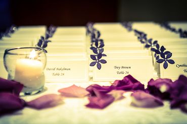 detail shot of the table assignments at the reception with purple flower petals and candlelight