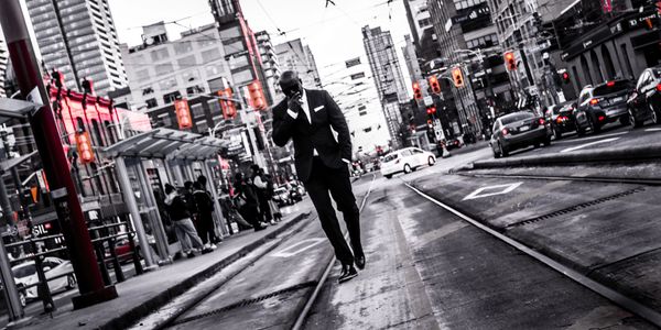 mysterious man walking in the middle of a busy city streetscape.