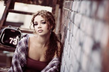 photo of a young woman leaning on a brick wall white cool matte tones