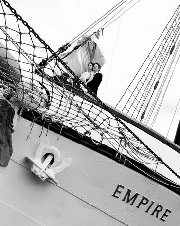 black and white photo of a bride and groom on the deck of sailboat