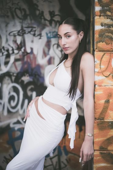 beautiful model in white in a grafittied alleyway